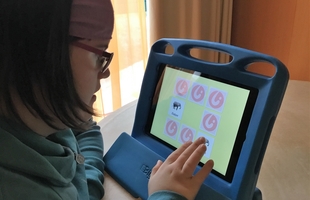 Foto: junges Mädchen mit Down-Syndrom bedient ein iPad- Foto: junges Mädchen mit Down-Syndrom bedient ein iPad-